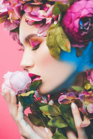 Beauty portrait. Beautiful brunette woman with sensual lilac lips surrounded by flowers. Spring look. Cosmetics, make-up. Perfumery.の写真素材