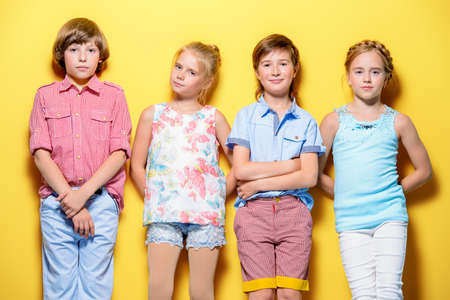 Bright summer children. Group of joyful children posing together over bright yellow background.の写真素材