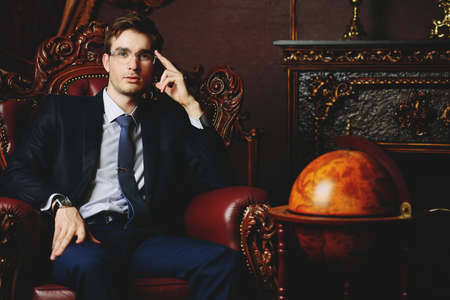 Handsome well-dressed young man in a room with classic interior. Business style. Luxury.の写真素材
