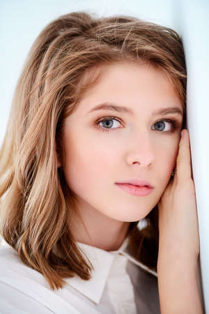 Portrait of a cute girl teenager leaned against the white wall. Beauty, fashion.の写真素材