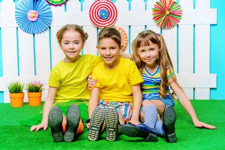 Happy joyful children are on a green lawn in a summer garden. Children's fashion. Happiness, activity and child concept. の写真素材