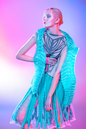 Fashion shot of a beautiful female model posing in designer clothes collection over pink background....