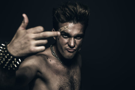 Bad boy concept. A portrait of a bad guy demonstrating antisocial behavior, rudeness and aggression. Rocker, punk. の写真素材