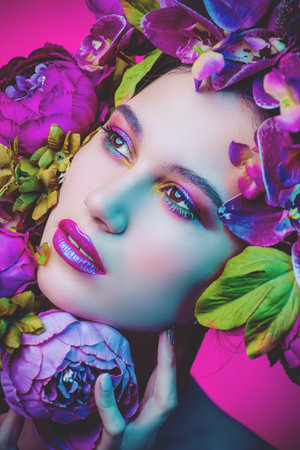 Beauty portrait. Beautiful brunette woman with sensual lilac lips surrounded by flowers. Spring...