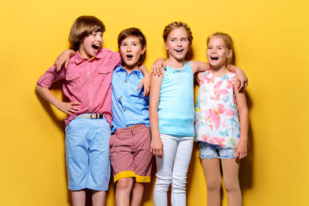 Bright summer children. Group of joyful children posing together over bright yellow background.の写真素材