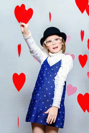 Valentine's Day concept. Happy pre-teen girl poses surrounded by little hearts. First love.の写真素材