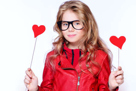 Portrait of a cute pre-teen girl holding two little hearts. Isolated over white. First love. Valentine's Day. の写真素材