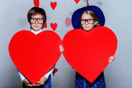 Happy pre-teen boy and girl holding two red hearts. Friendship. First love. Valentine's Day. の写真素材