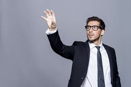 Contemporary businessman hand touching empty virtual screen. Studio shot. Copy space. Modern business technologies concept.の写真素材