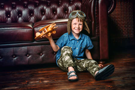 Cute dreamer boy playing with toy airplane at home. Childhood. Fantasy, imagination. の写真素材