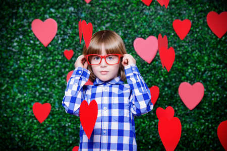 Ð¡ute child boy surrounded by hearts over lawny background. First love. Valentine's Day. の写真素材