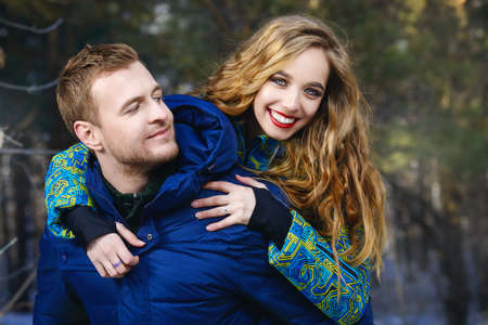 Couple of young people in winter clothes in the park. Winter fashion. Down jacket.の写真素材