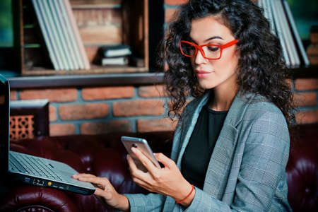 Businesswoman is working with a laptop and cell phone at the office.の写真素材