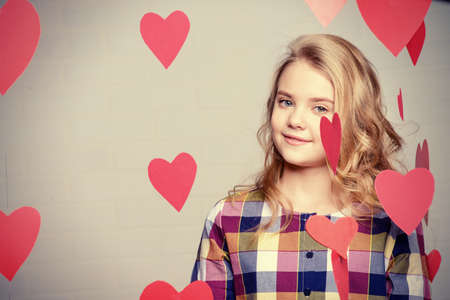 Valentine's Day concept. Happy pre-teen girl poses surrounded by little hearts. First love.の写真素材