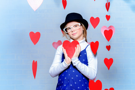 Valentine's Day concept. Happy pre-teen girl poses surrounded by little hearts. First love.