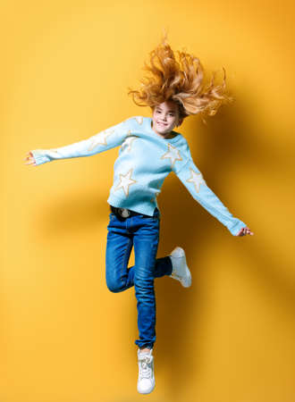 Joyful pre-teen girl jumping over yellow background. Full length studio shot. Happiness, activity and child concept.の写真素材