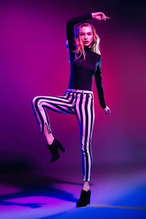 Attractive fashionable young woman wearing in hat, striped trousers and boots. Youth style. Studio shot.の写真素材