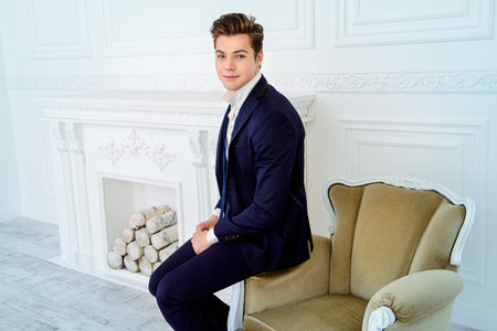 Handsome young man in elegant suit posing in luxurious apartments. Male beauty, fashion.