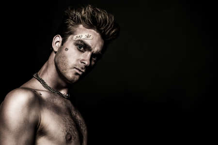 Bad boy concept. Close-up portrait of a bad guy showing rudeness and aggression. Rocker, punk. の写真素材