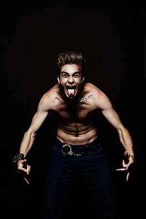 Bad boy concept. A portrait of a bad guy demonstrating antisocial behavior, rudeness and aggression. Rocker, punk. の写真素材