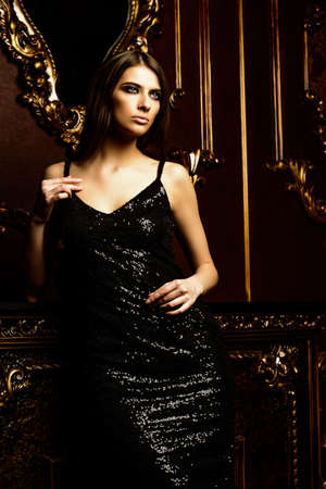 Portrait of an attractive young woman in tight black dress in a luxury apartment.の写真素材