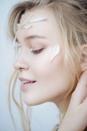 Beautiful young woman with petals of chrysanthemum on face and body.の写真素材
