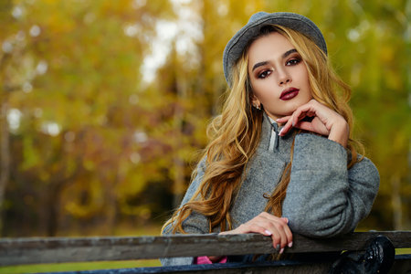 Attractive fashionable young woman walking in a beautiful autumn park.の写真素材