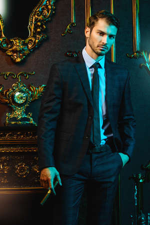 Portrait of an imposing man in an expensive suit smoking a cigar.の写真素材