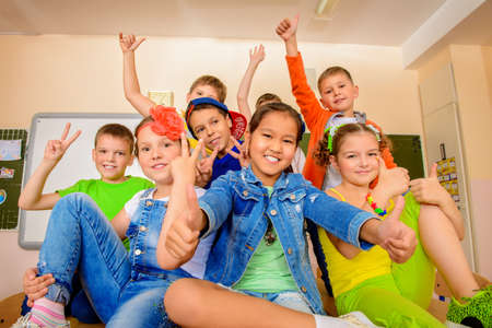 Group of happy classmates in bright casual clothes posing together at a classroom. Education.の写真素材