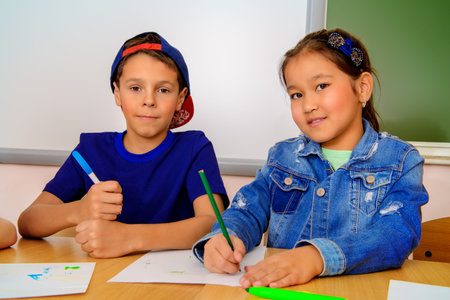 Happy school time. Two smiling children sitting at the desk in the classroom. Education.