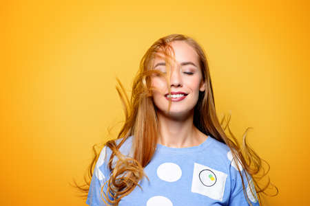 Cute girl with beautiful long flying hair over yellow background. Healthy hair, haircare.の写真素材