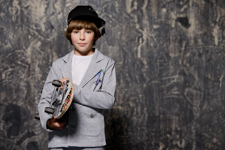 Happy cool boy boy holds a skateboard. Kid's fashion.