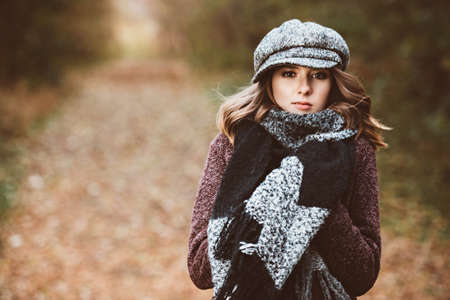 Cute teen girl in modern clothes posing outdoor. Warm autumn day. Seasonal autumn and winter fashion.の写真素材