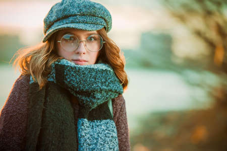 Cute teen girl in modern clothes posing outdoor. Warm autumn day. Seasonal autumn and winter fashion.の写真素材