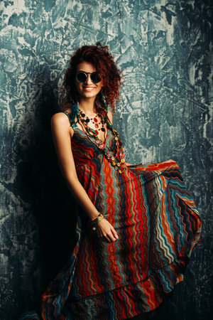 Beautiful bright woman with curly foxy hair wears a dress and beads in boho style. Ethnic style in clothes.の写真素材