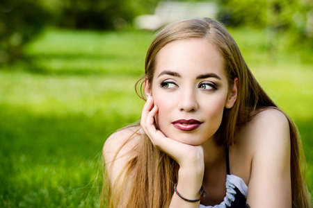 Happy summer day. Pretty young woman having a rest on a green lawn in a summer park. Beauty, fashion.  の写真素材