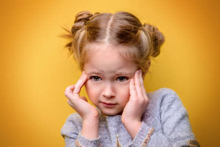 Close-up portrait of a cute little girl. Studio shot over yellow background. Childhood concept.の写真素材