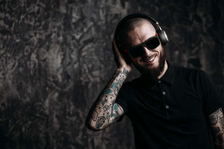 Brutal bearded man wearing sunglasses listenig to music in headphones and smiling.の写真素材