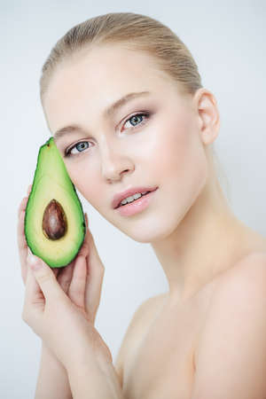 Beautiful young woman with avocado. Beauty, natural cosmetics concept. Spa, body care.の写真素材