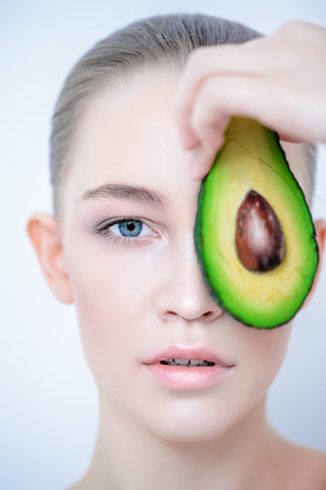 Beautiful young woman with avocado. Beauty, natural cosmetics concept. Spa, body care.