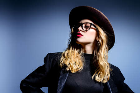 Attractive fashionable young woman wearing in hat and glasses. Optics style. Studio shot.の写真素材