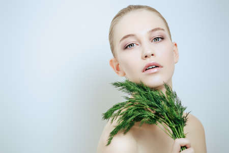 Beautiful young woman with bunch of dill. Beauty, natural cosmetics concept. Spa, body care.の写真素材