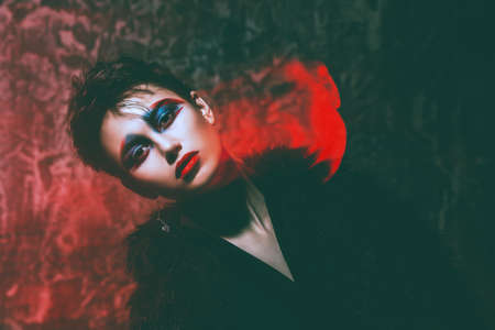 Female fashion model posing in red light. Stylish clothes and creative makeup. Beauty, fashion. Studio shot.の写真素材