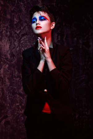 Female fashion model posing in red light. Stylish clothes and creative makeup. Beauty, fashion. Studio shot.の写真素材