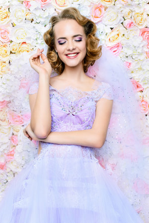 Charming bride in a beautiful dress posing by a background of roses. Wedding fashion. の写真素材