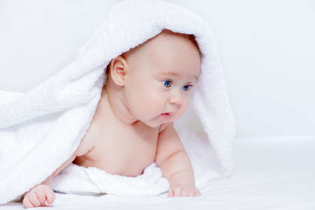Sweet baby under a white towel after bath. Healthcare, pediatrics.の写真素材