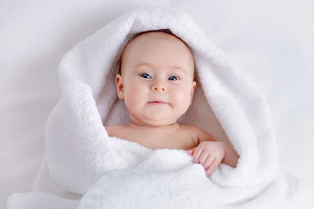 Sweet baby in a white towel after bath. Healthcare, pediatrics.の写真素材