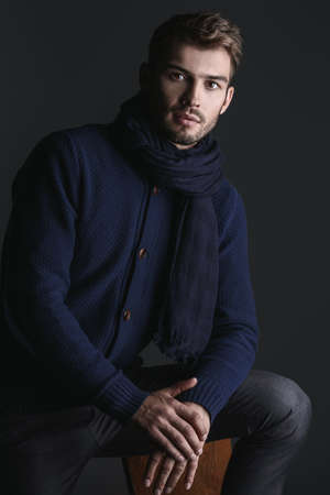 Handsome young man in scarf and sweater. Studio portrait. Autumn and winter clothing. Male fashion.の写真素材