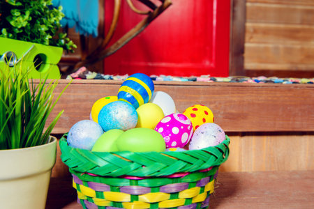 Easter holiday. Basket with painted eggs is on the porch of a wooden house. Rural style, easter...