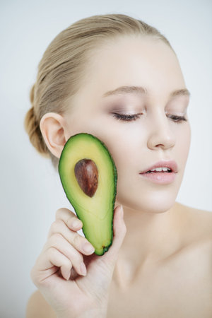 Beautiful young woman with avocado. Beauty, natural cosmetics concept. Spa, body care.